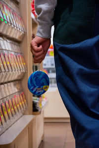 Midsection of man holding lollipop in store