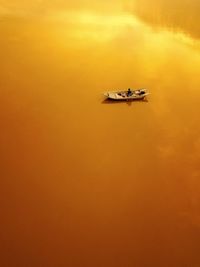 Man sitting in boat on sea during sunset