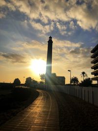 Walkway amidst buildings against sky during sunset