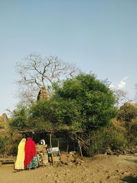 Rear view of women sitting on field against sky