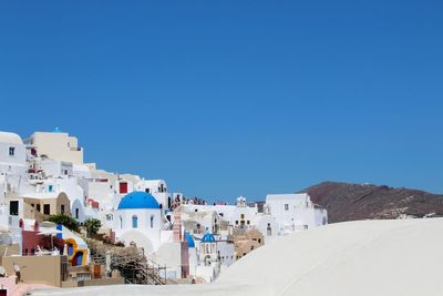 Buildings in city against clear blue sky