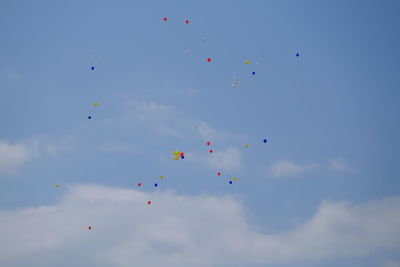 Low angle view of balloons flying against blue sky