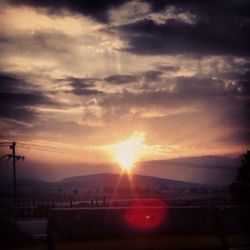 Sun shining through clouds over mountains