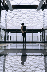 Full length rear view of man walking on tiled floor