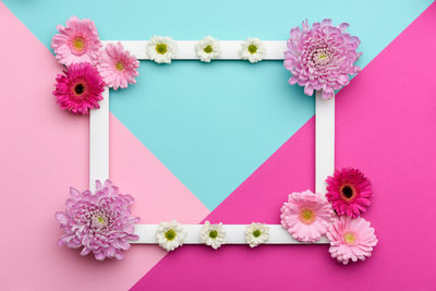 Directly above shot of pink flowers and picture frame on table