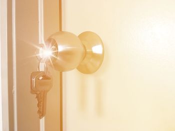 Close-up of light bulb hanging against wall at home