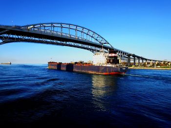 View of bridge over sea against clear blue sky