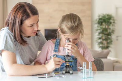 Mother helping daughter in science project at home
