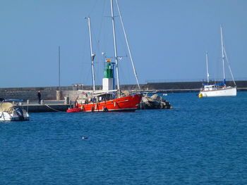 Sailboats in habor against clear blue sky