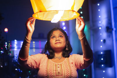 Indian girl celebrating diwali by releasing sky lantern into the sky as part of a rituals