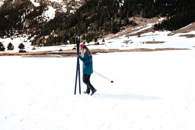 Side view of unrecognizable lady in warm clothes skiing on snow on background of mountain ridge