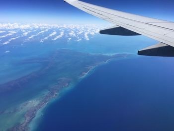 Aerial view of airplane wing over landscape against blue sky