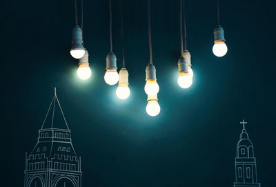 Low angle view of illuminated light bulbs at night