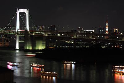 Illuminated bridge over river at night