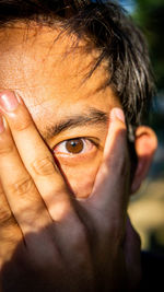 Close-up portrait of man covering face with hand