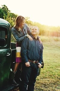 Happy woman looking at man while standing on pick-up truck