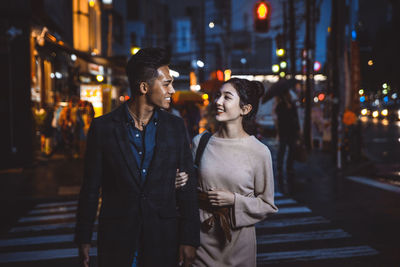 Smiling couple standing on illuminated street at night