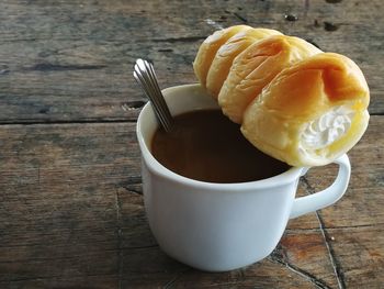 Close-up of cream roll with hot chocolate on wooden table