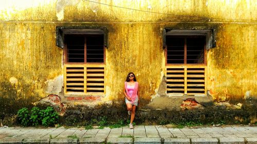 Portrait of woman standing against wall of building