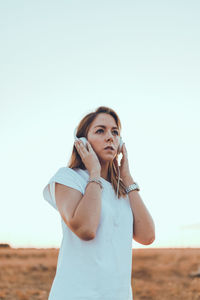 Portrait of beautiful woman standing on land against clear sky