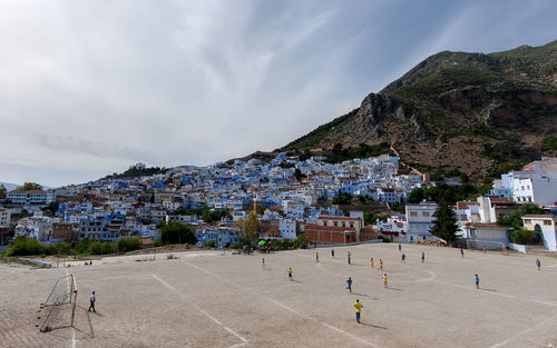 People playing soccer by houses and mountain