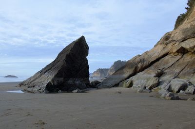 Rock formations on beach against sky