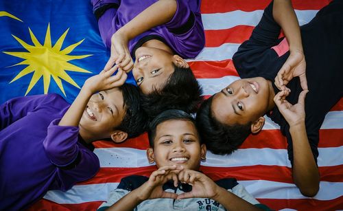 Portrait of happy friends lying on malaysian flag