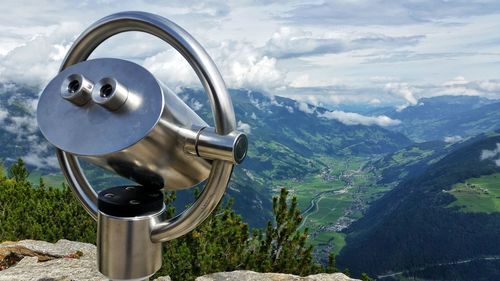 Close-up of coin-operated binoculars against mountains