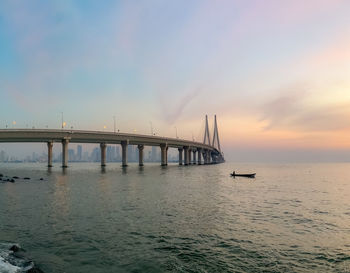 Bridge over sea against sky during sunset