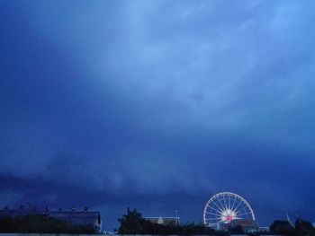 Low angle view of ferris wheel against cloudy sky