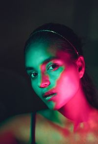 Close-up portrait of young woman against black background