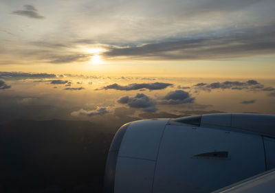 Airplane flying over clouds during sunset