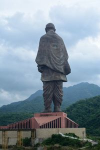 Rear view of statue of unity against cloudy sky