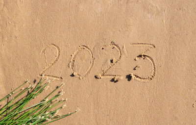 The numbers 2023 are written on the sand on the beach.happy new year 2023 background. 