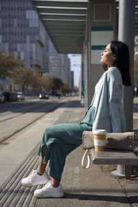 Businesswoman with eyes closed sitting on bench at tram station