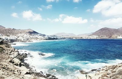Scenic view of sea and mountains against blue sky