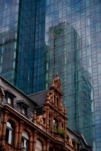 Low angle view of old building against glass office skyscraper