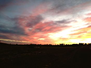 Scenic view of dramatic sky over land during sunset