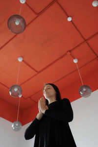 Young woman standing against illuminated ceiling