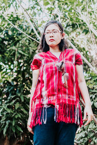 Young woman standing against plants