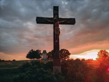 Cross at cemetery against sky during sunset