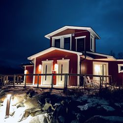 House by illuminated building against sky at dusk