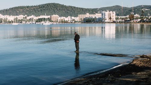 Man standing on pier amidst lake in city