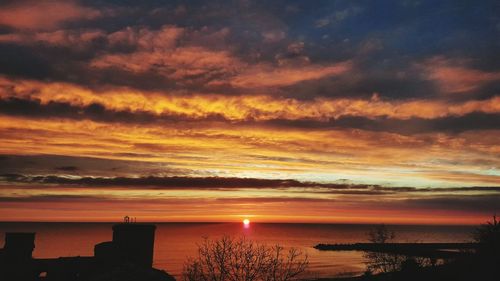 Scenic view of sea against dramatic sky during sunset