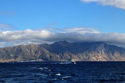 Scenic view of sea by mountains against sky