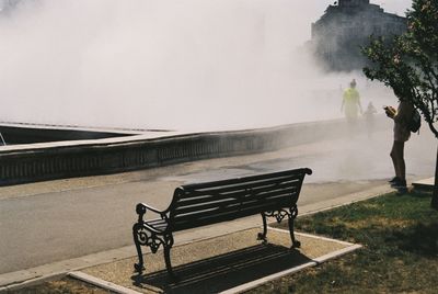 Bench against a misty backdrop with people walking into the mist