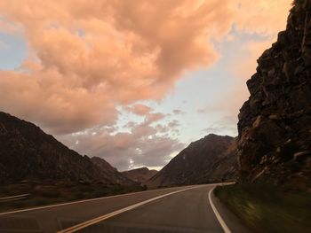 Road amidst mountains against sky during sunset