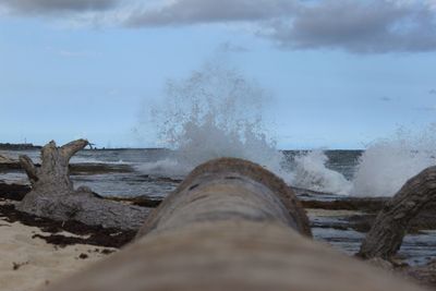 Close-up of waves splashing on beach against sky