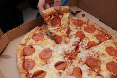 Midsection of person holding slice of pizza