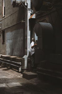 Side view of man standing against building